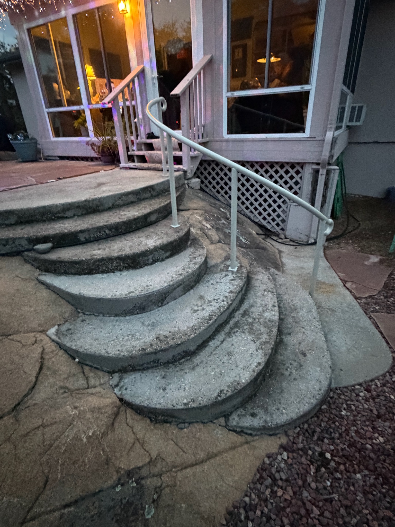 Curved custom handrail on circular concrete steps at dusk