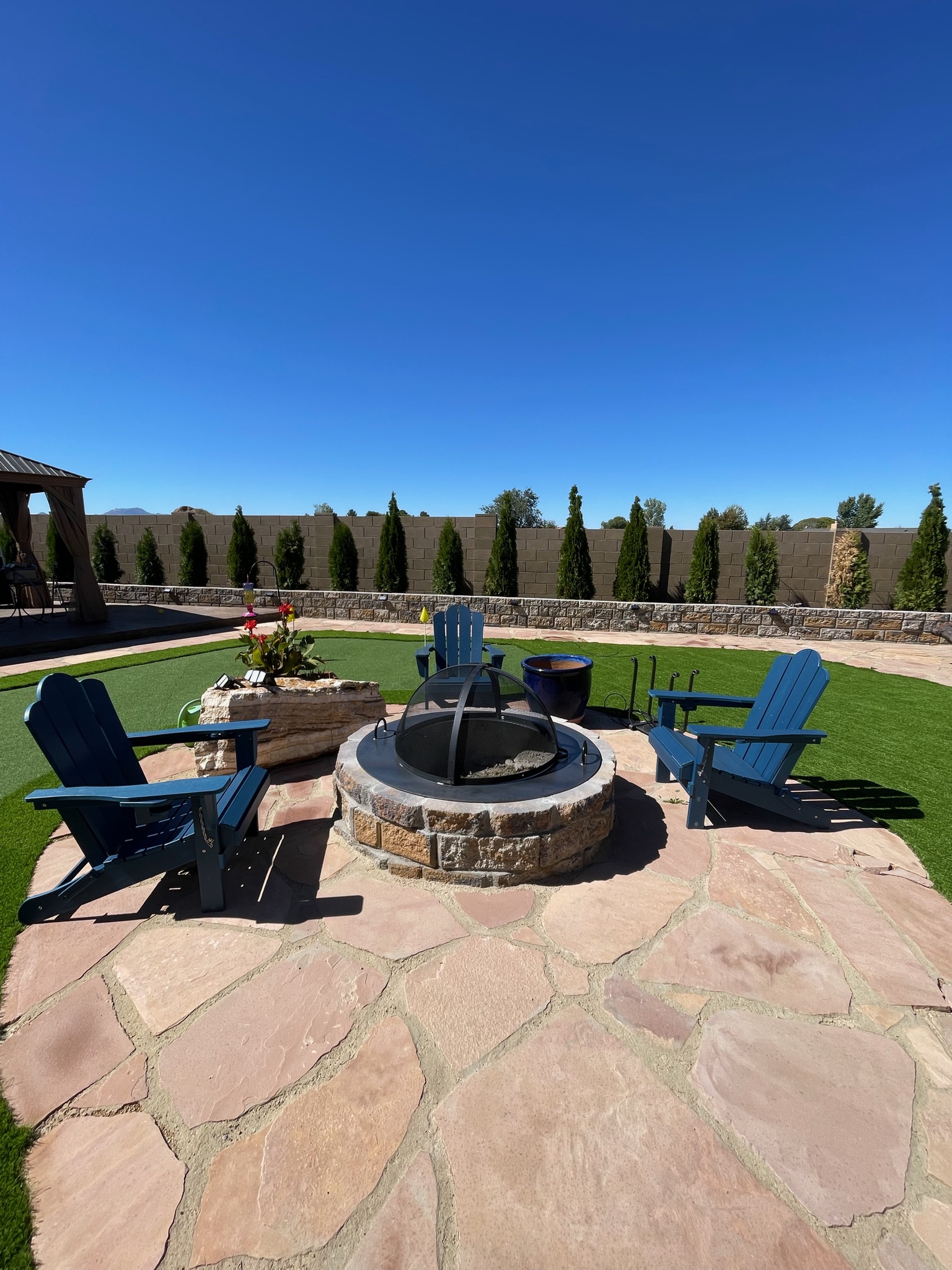 Stone fire pit with steel insert and dome spark screen on a flagstone patio