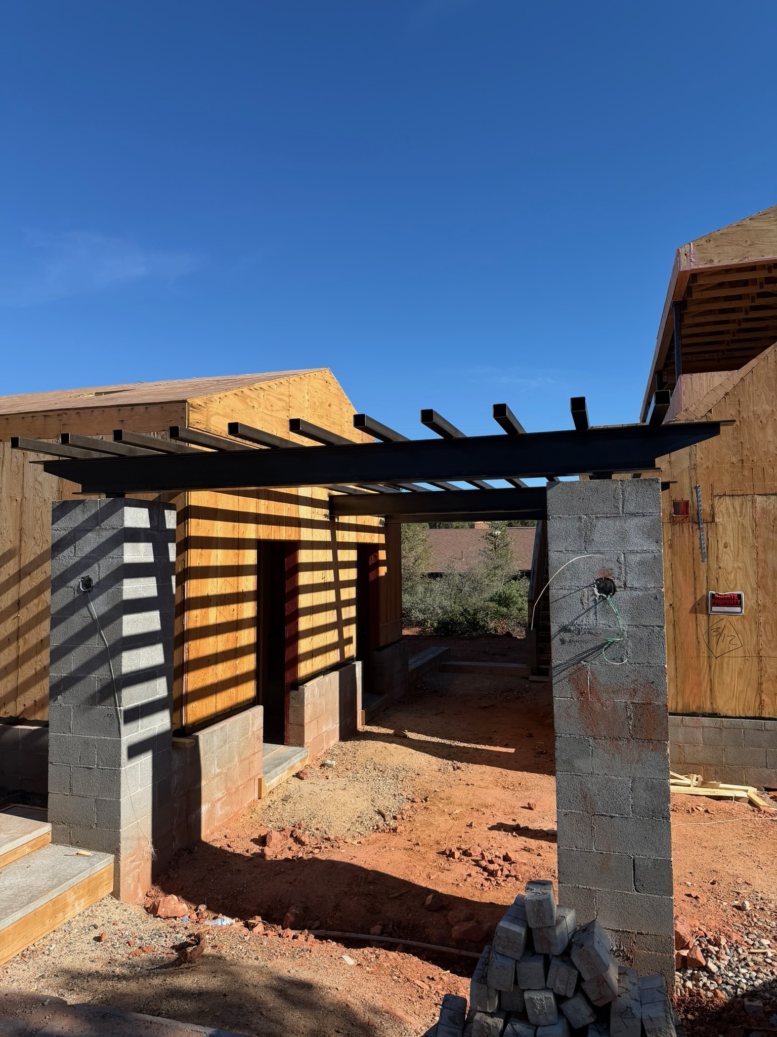Black steel shade trellis spanning block columns at a Sedona custom build