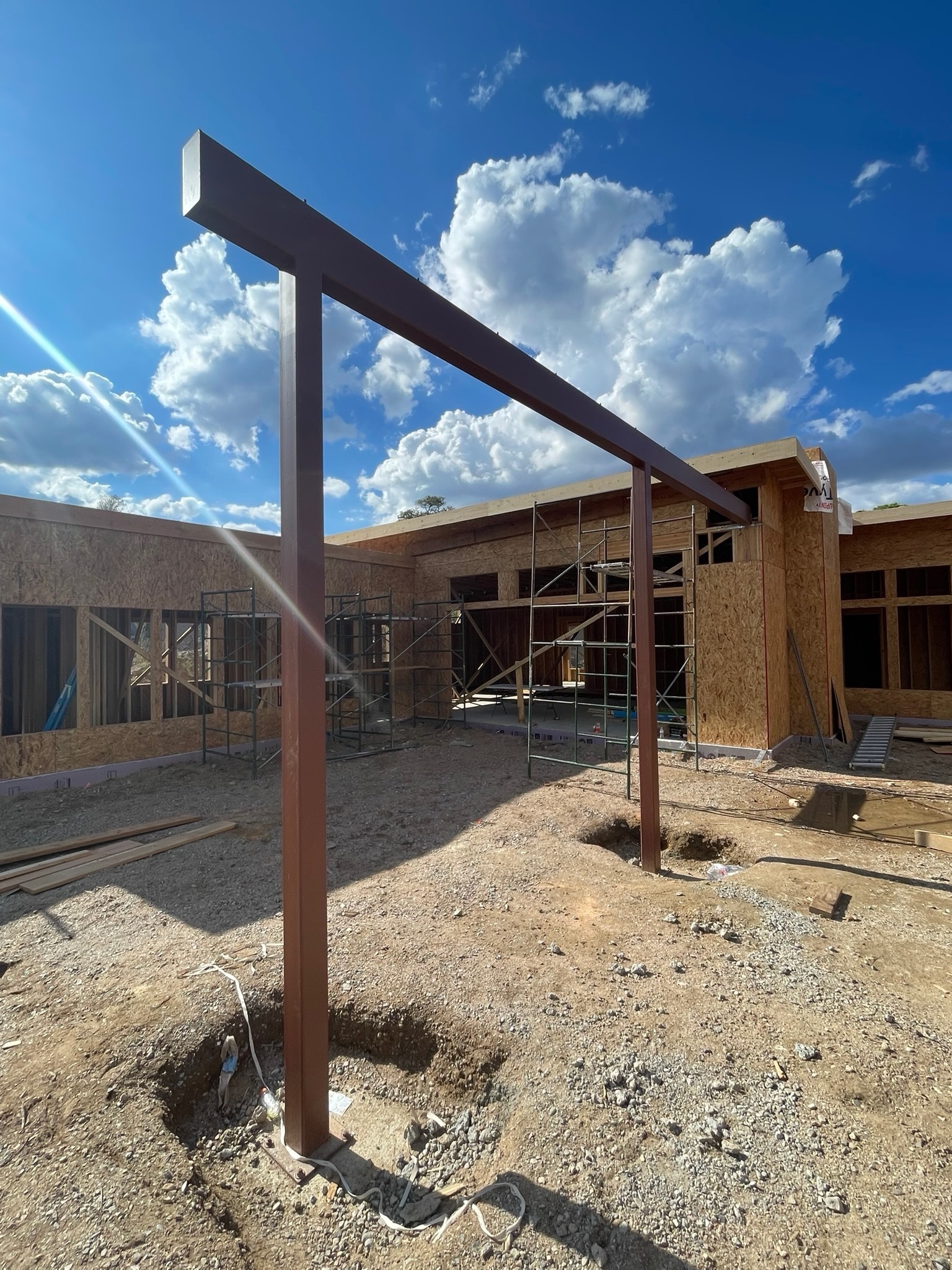 Steel column and beam frame set on anchor bolts at a custom home courtyard