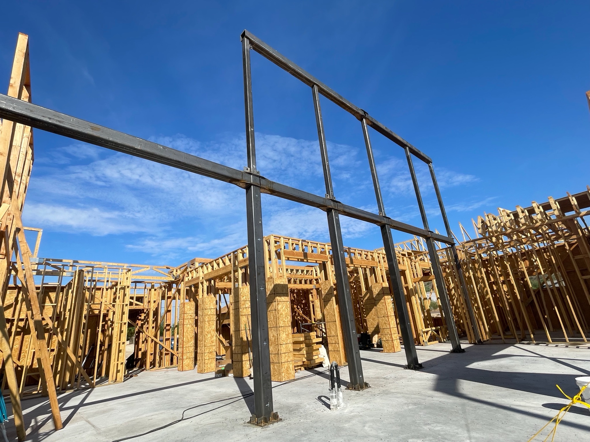 Welded steel moment frame erected within the wood framing of a residential build
